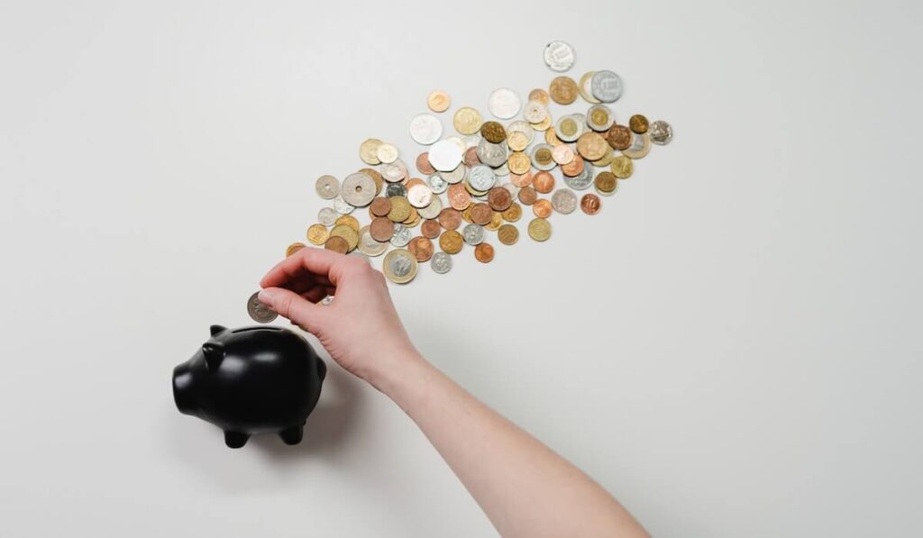 Hand Placing Coins in Piggy Bank
