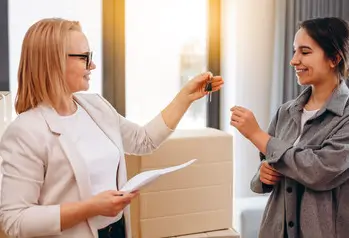 business woman handing property key to renter